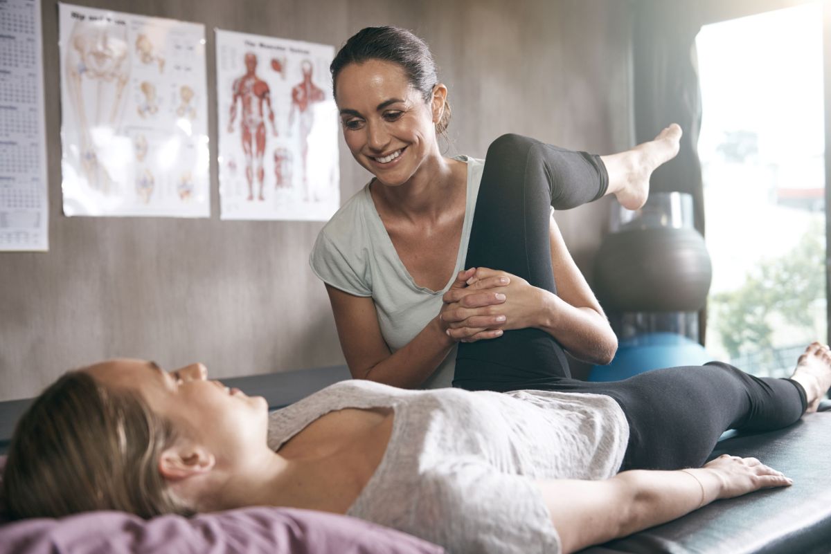 female physiotherapist assessing hip flexion of female patient