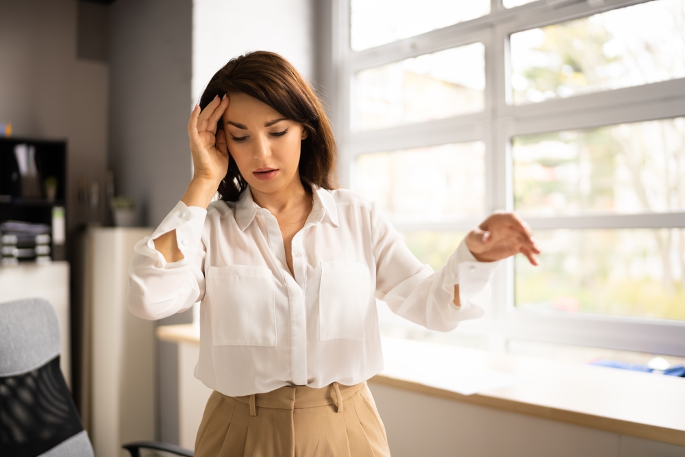Women standing with hand on head feeling dizzy