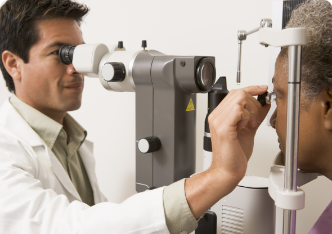 An eye doctor performing an eye exam on a patient using a slit lamp.