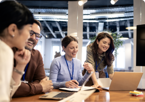 A diverse team of colleagues collaborating around a laptop in a modern office.