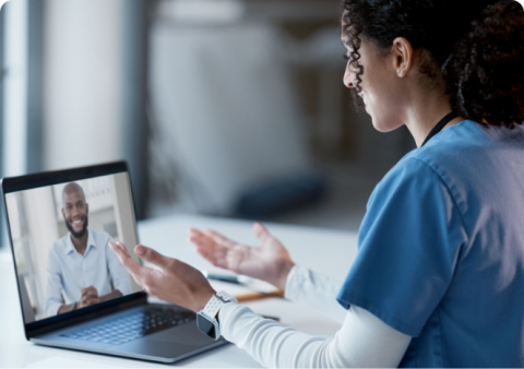 A female healthcare professional conducting a telehealth consultation via laptop.